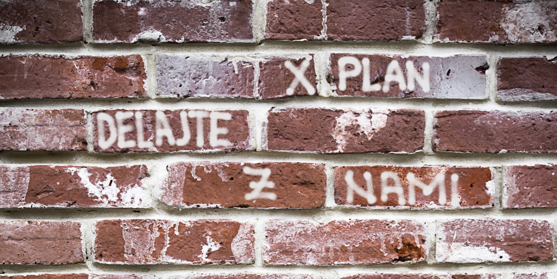 XPLAN – lavora con noi: un messaggio su una parete in mattoni.